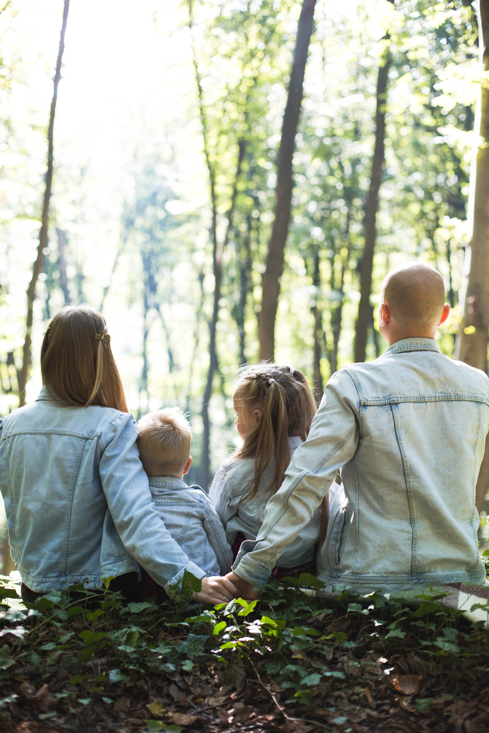 Couple holding hands sitting on the lawn with two little children.